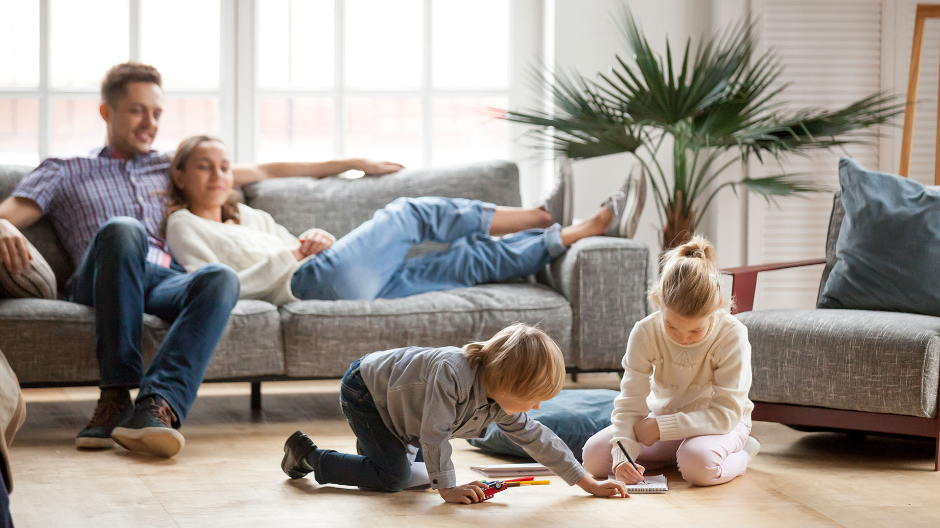 Children Playing on the Floor in the Living Room with Parents on a Sofa